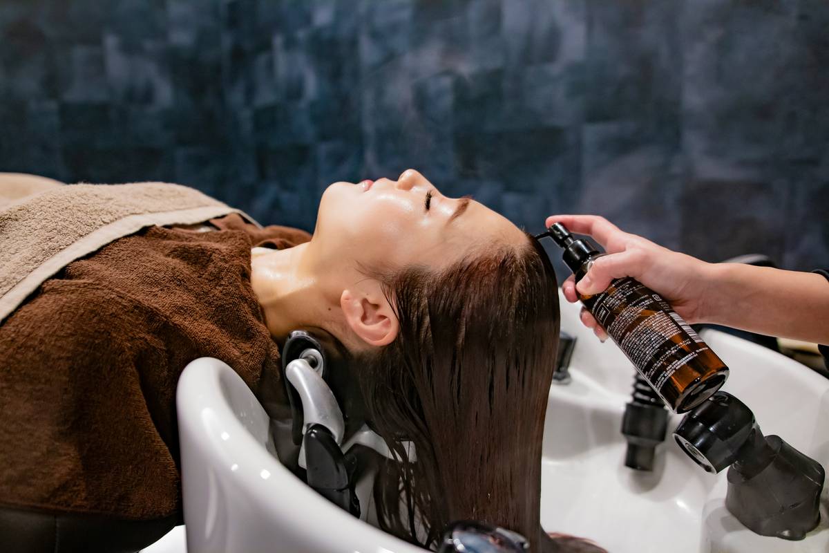 zinc korean hair salon client holding supplement bottle next to treatment chair